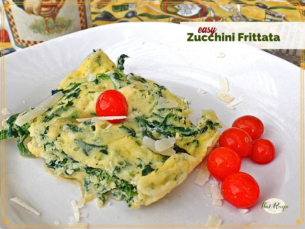 slice of zucchini frittata on a plate with tomatoes