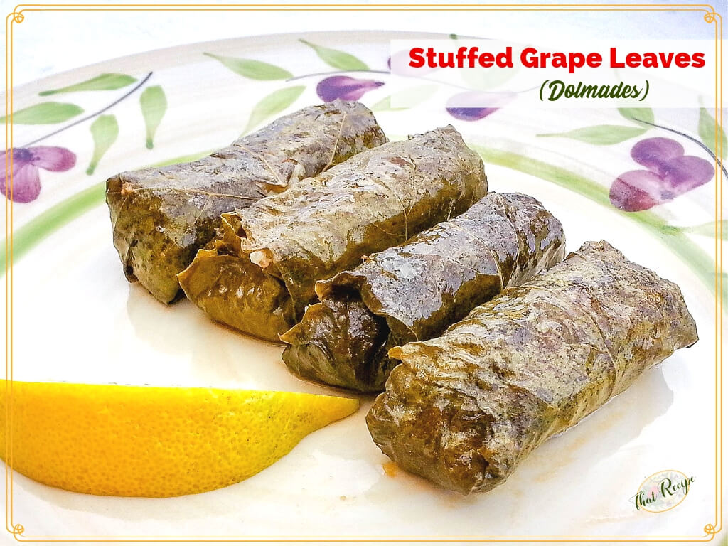 4 dolmades on a plate with a slice of lemon and text overlay "Stuffed grape leaves (dolmades)