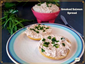smoked salmon spread on a bagel with a bowl of smoked salmon spread in a pink bowl.