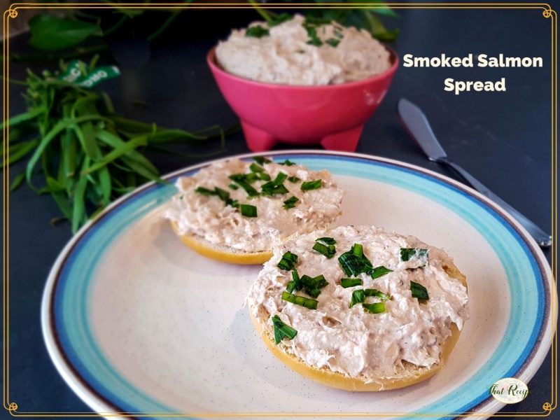 smoked salmon spread on a bagel with a bowl of smoked salmon spread in a pink bowl.
