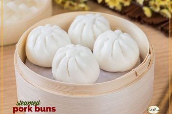 pork buns in a bamboo steamer with text overlay "steamed pork buns"