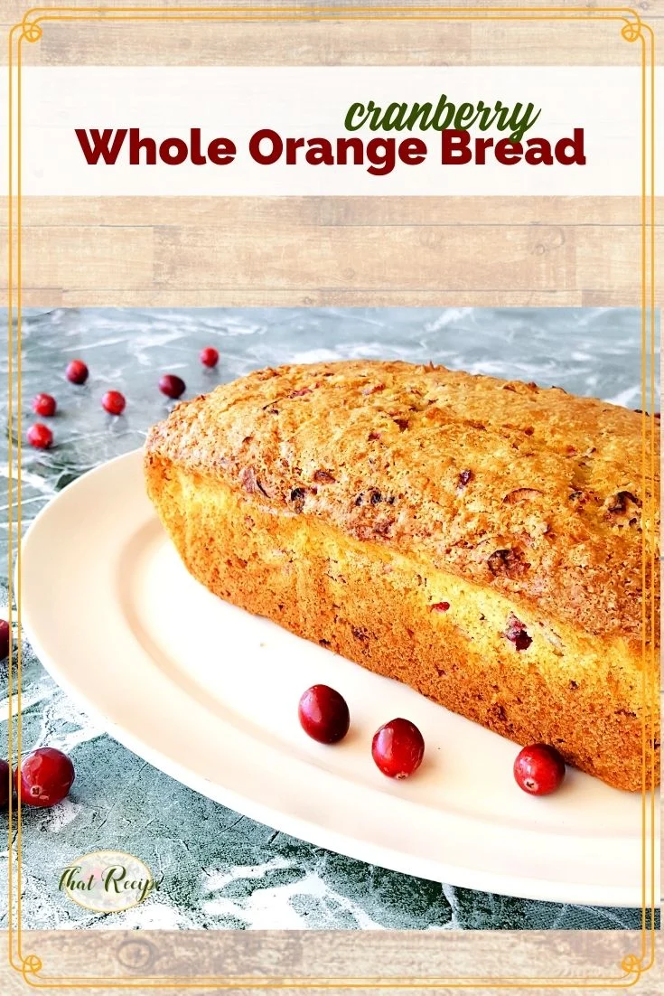 loaf of quick bread on a plate surrounded by cranberries with text overlay "Cranberry whole orange bread".