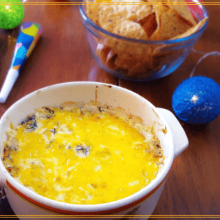 cheesy kale dip and chips on a table with party favors