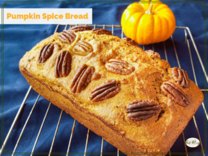 loaf of pumpkin spice bread on cooling rack with mini pumpkin