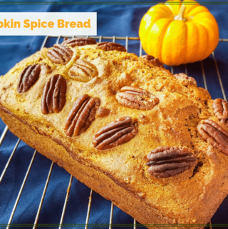 loaf of pumpkin spice bread on cooling rack with mini pumpkin