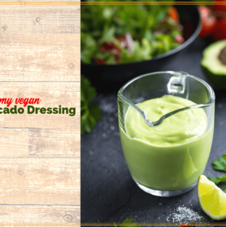 avocado salad dressing in a glass jug on a table with salad and text overlay "creamy vegan Avocado Salad Dressing"