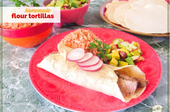steak burrito on a plate with Mexican rice, avocado salsa and flour tortillas in the background with text overlay "homemade flour tortillas"