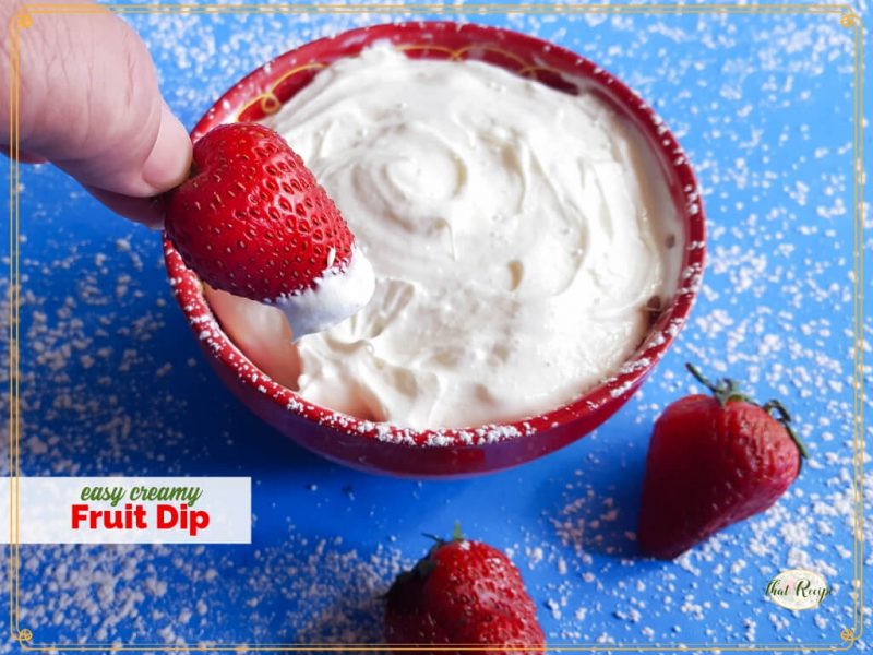 strawberry being dipped in bowl of creamy dip with text overlay "easy creamy fruit dip"