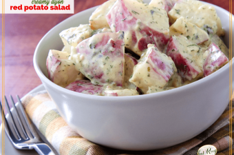 bowl of red potato salad on a table with text overlay "Creamy Dijon Potato Salad"