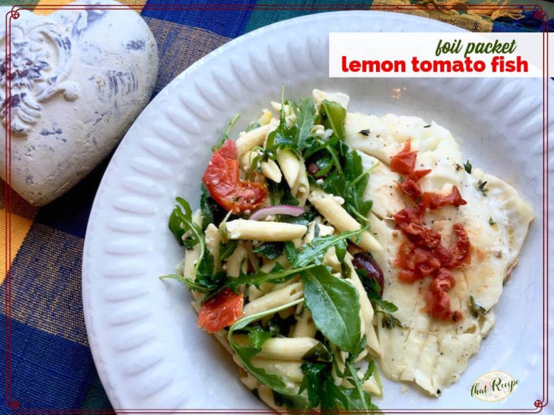 top down view of fish and pasta salad on a plate with text overlay "foil packet lemon tomato fish"
