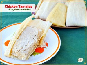 opened chicken tamale on a plate with plate of unopened tamales