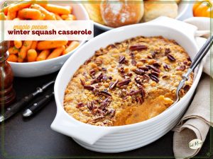 squash casserole on a table with carrots and rolls.