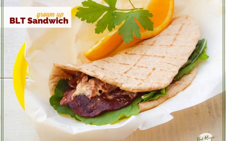 BLT pita wrap with orange slices and text overlay "grown Up BLT Sandwich"