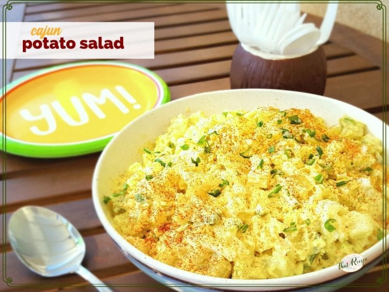 bowl of potato salad on a picnic table with text overlay "cajun potato salad"