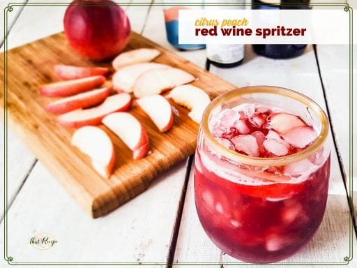 glass of red wine spritzer with peach slices on a cutting board "citrus peach red wine spritzer"
