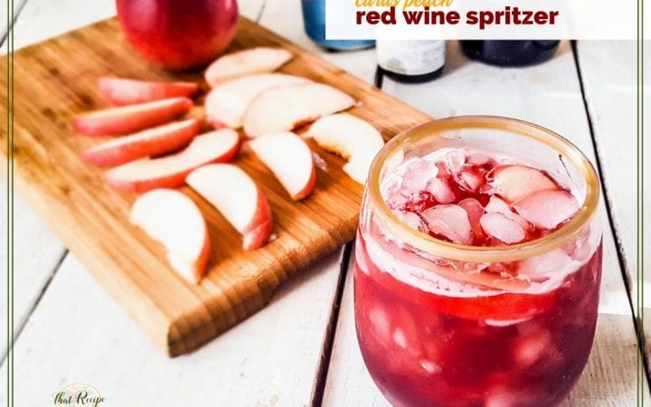 glass of red wine spritzer with peach slices on a cutting board "citrus peach red wine spritzer"