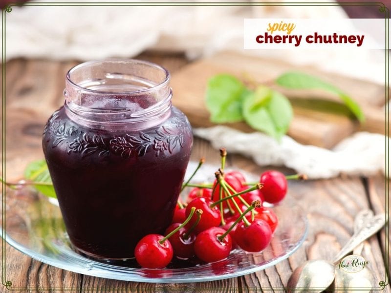 jar of cherry chutney with with fresh cherries and text overlay "spicy cherry chutney"