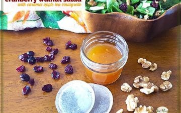 salad dressing in a jar with cranberries, walnuts, tea bags and a salad bowl around it and text overlay "cranberry walnut salad with caramel apple tea dressing"