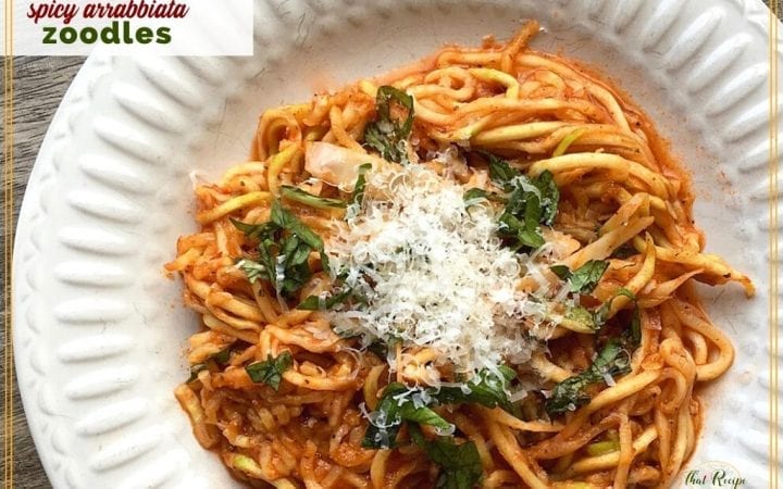 zucchini noodles with pasta sauce and parmesan on a plate with text overlay "spicy Arrabbiata Zoodles"