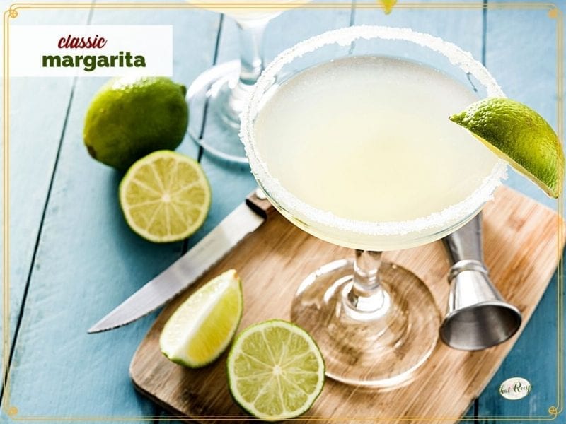 margarita in a glass surrounded by cut limes with text overlay "classic margarita"