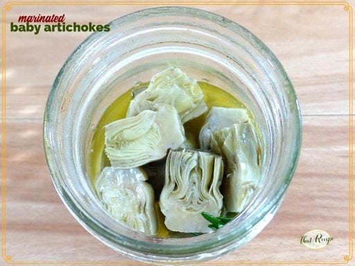 baby artichokes in a jar with text overlay "marinated baby artichokes"