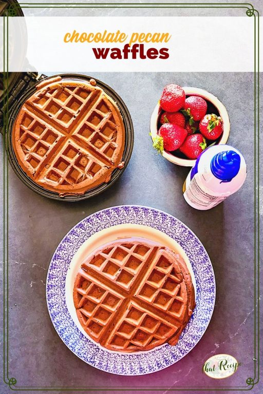 waffles on a plate and on a waffle iron with strawberries and whipped cream and text overlay "chocolate pecan waffles"