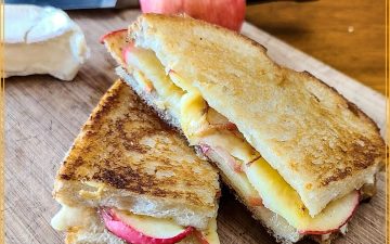 grilled cheese sandwich on cutting board with brie and apple