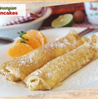 rolled pancakes on a plate with orange slices and text overlay " Norwegian Pancakes"