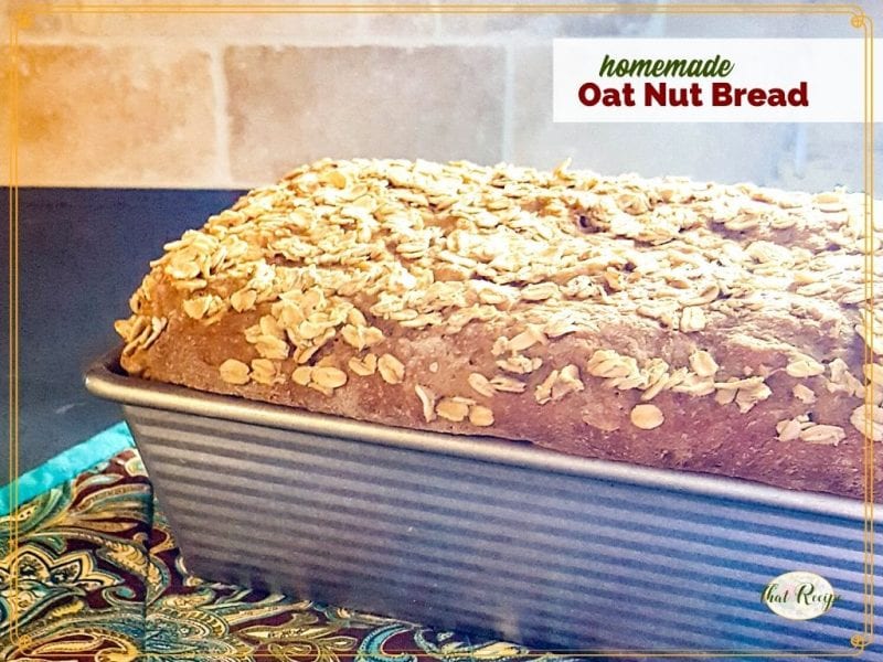 loaf of oatmeal bread in the pan on a counter with text overlay "homemade Oat Nut Bread"
