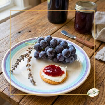 lavender stalks, bunch of red grapes, cracker with cream cheese and grape jelly