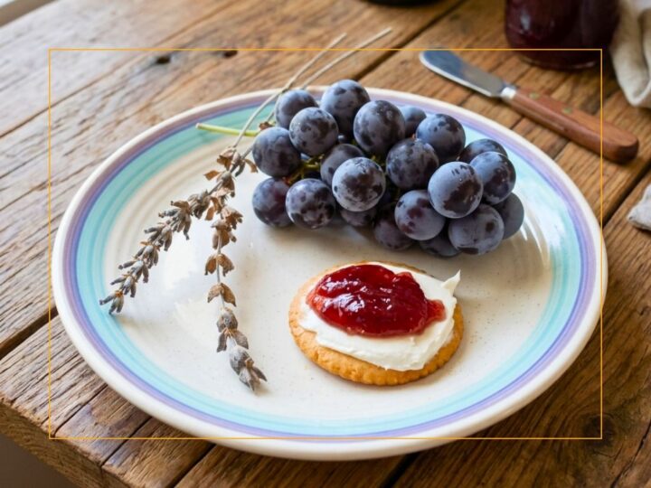 lavender stalks, bunch of red grapes, cracker with cream cheese and grape jelly