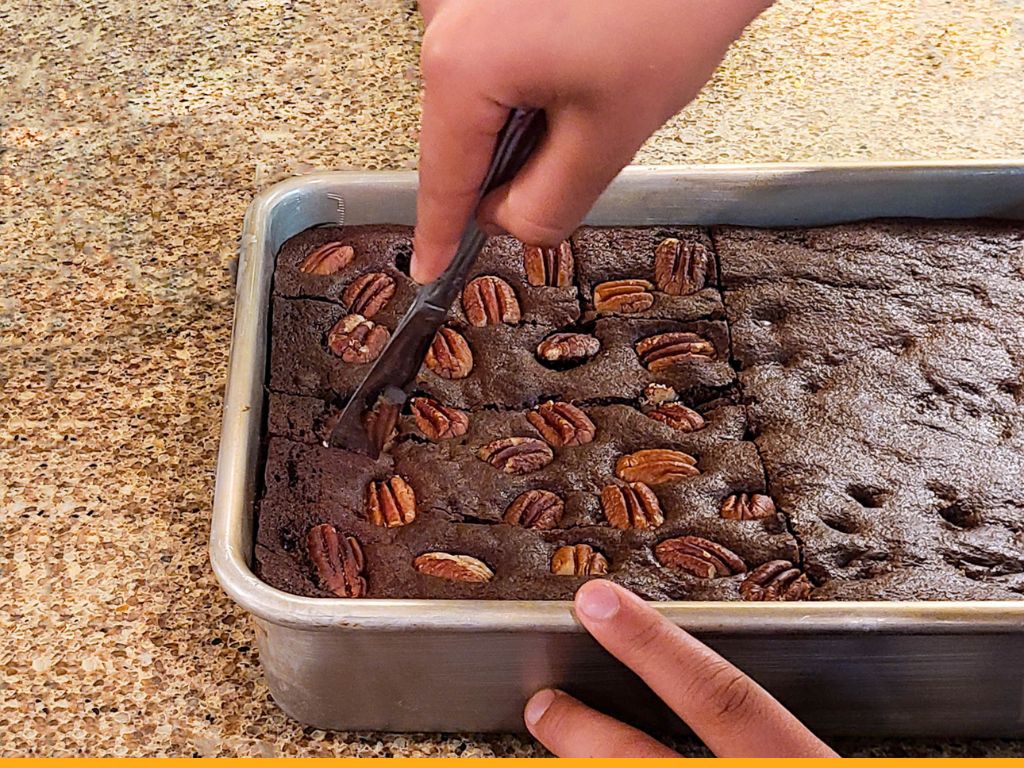 hand cutting brownies in a pan