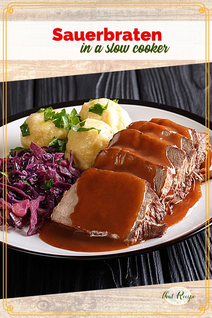 sliced sauerbraten on a plate with gravy, potatoes and red cabbage