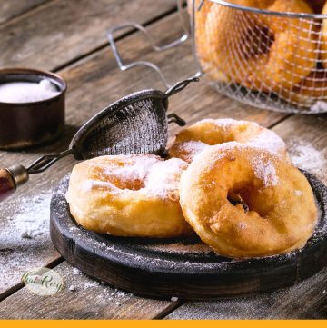 homemade donuts on a plate with powdered sugar