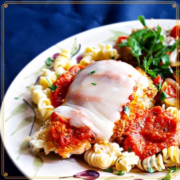 baked chicken parmesan on a plate with pasta and vegetables