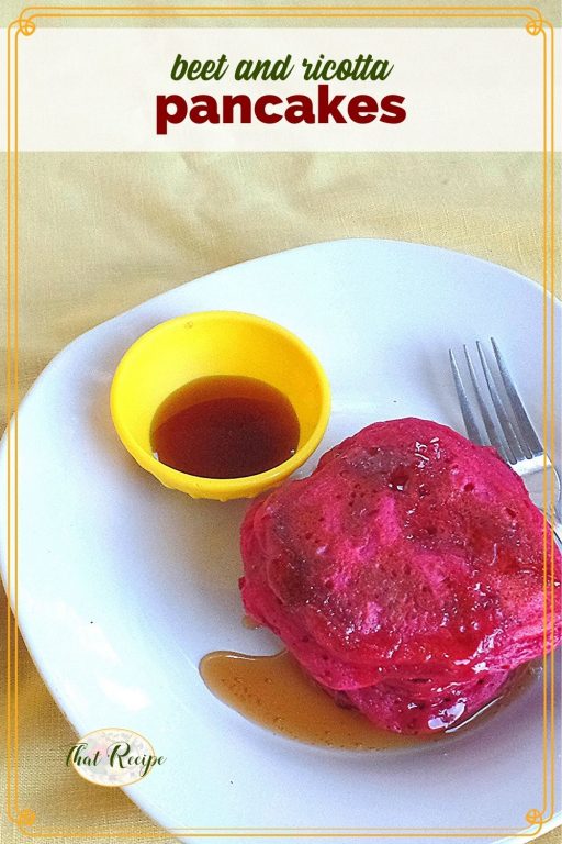 stack of pink pancakes on a plate with maple syrup and text overlay "beet ricotta pancakes"