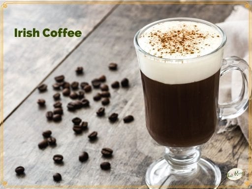 glass mug of Irish Coffee surrounded by coffee beans