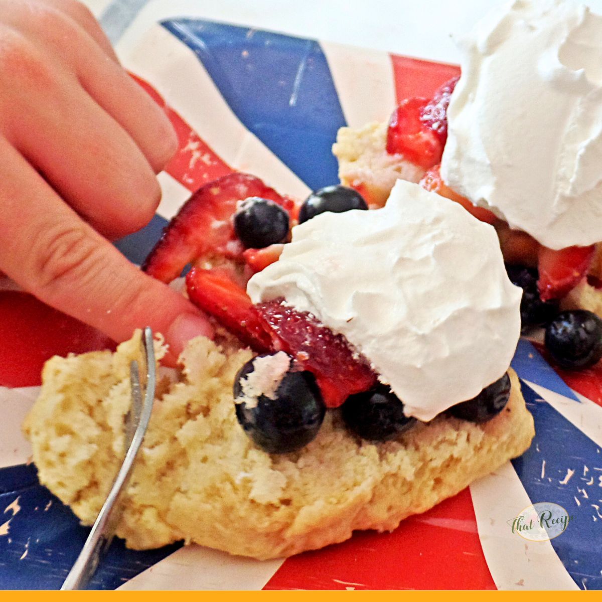 child hand cutting berry shortcake