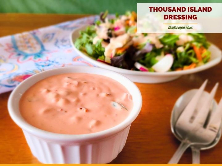 cup of thousand island dressing with a salad in background