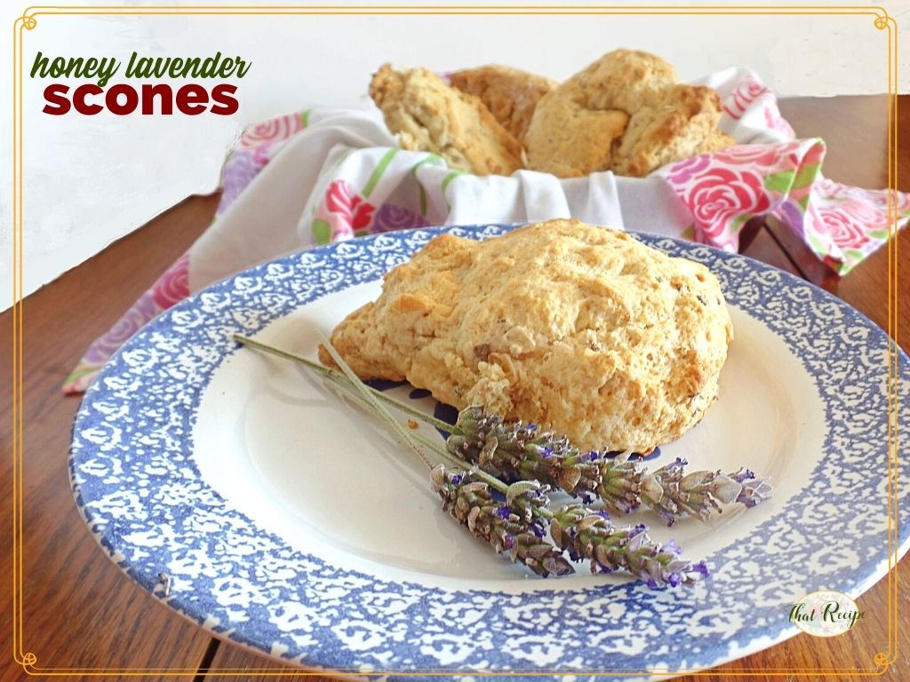 scone on a plate with fresh lavender and bowl of more scones in background with text overlay "honey lavender scones"