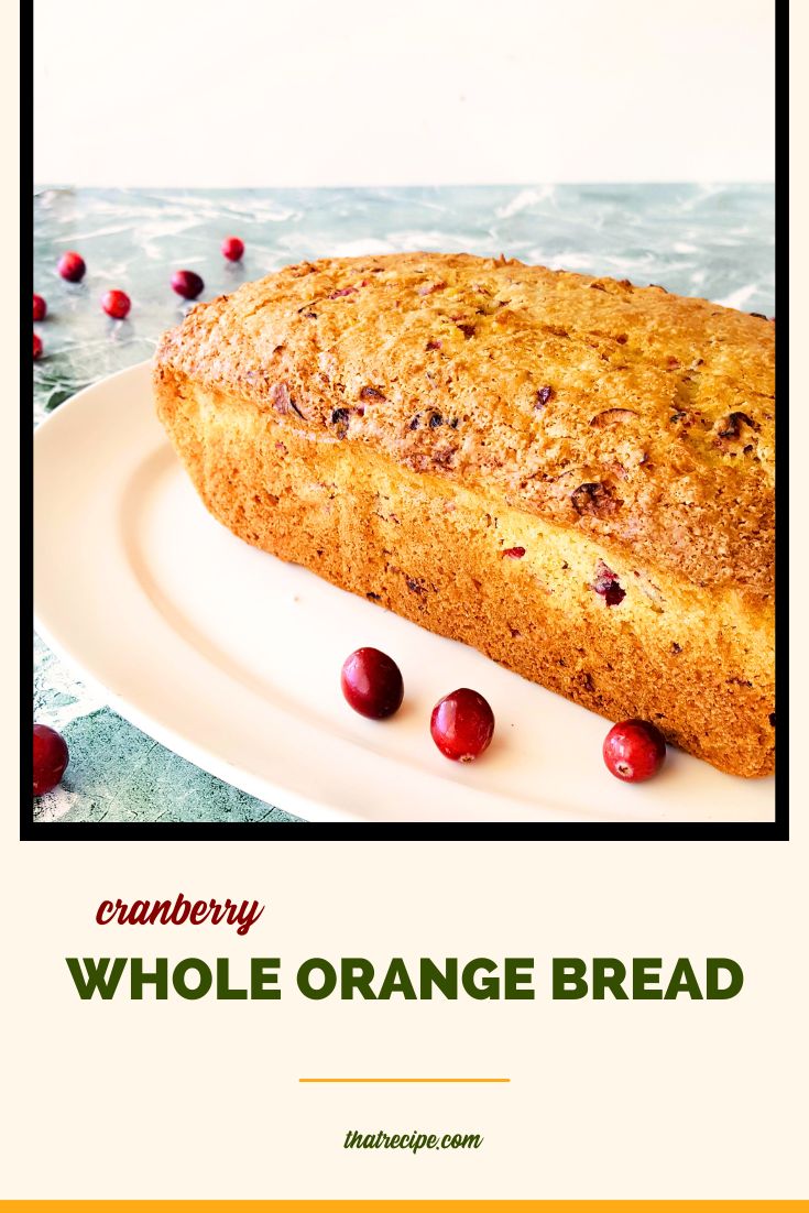 loaf of quick bread on a plate surrounded by cranberries with text overlay "Cranberry whole orange bread"
