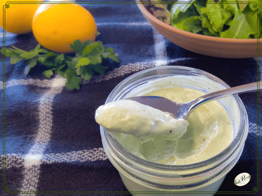 preserved lemon and herb salad dressing in a jar with a plate of salad