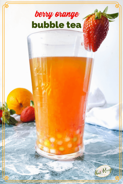 glass of berry orange boba tea with strawberries and orange in background