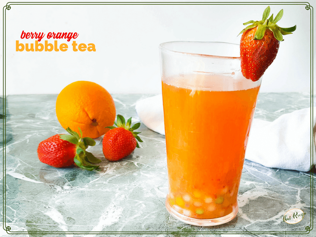 glass of berry orange boba tea with strawberries and orange in background