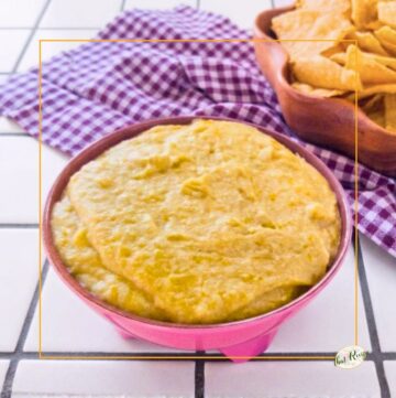 hot artichoke dip in a bowl next to tortilla chips
