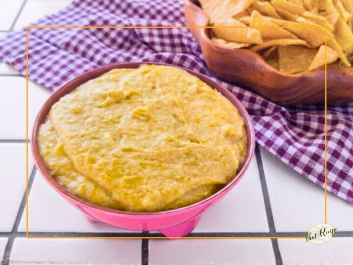 hot artichoke dip in a bowl next to tortilla chips