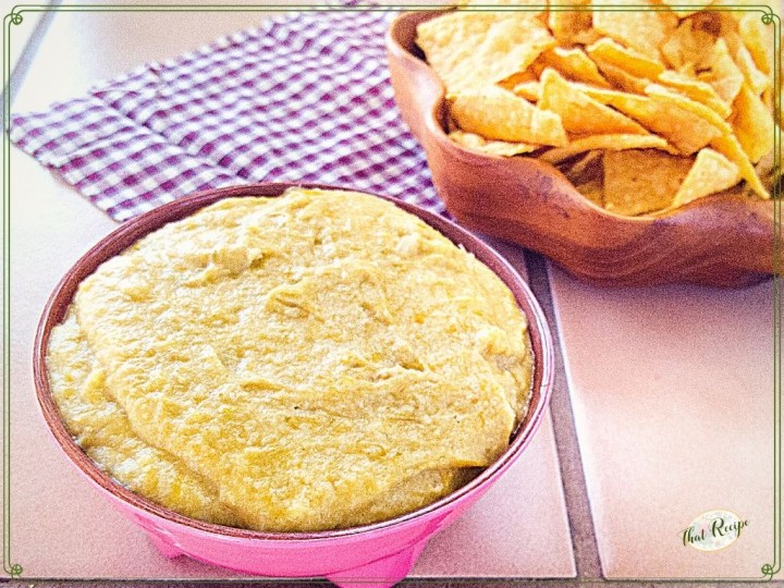 hot artichoke dip in a bowl next to tortilla chips