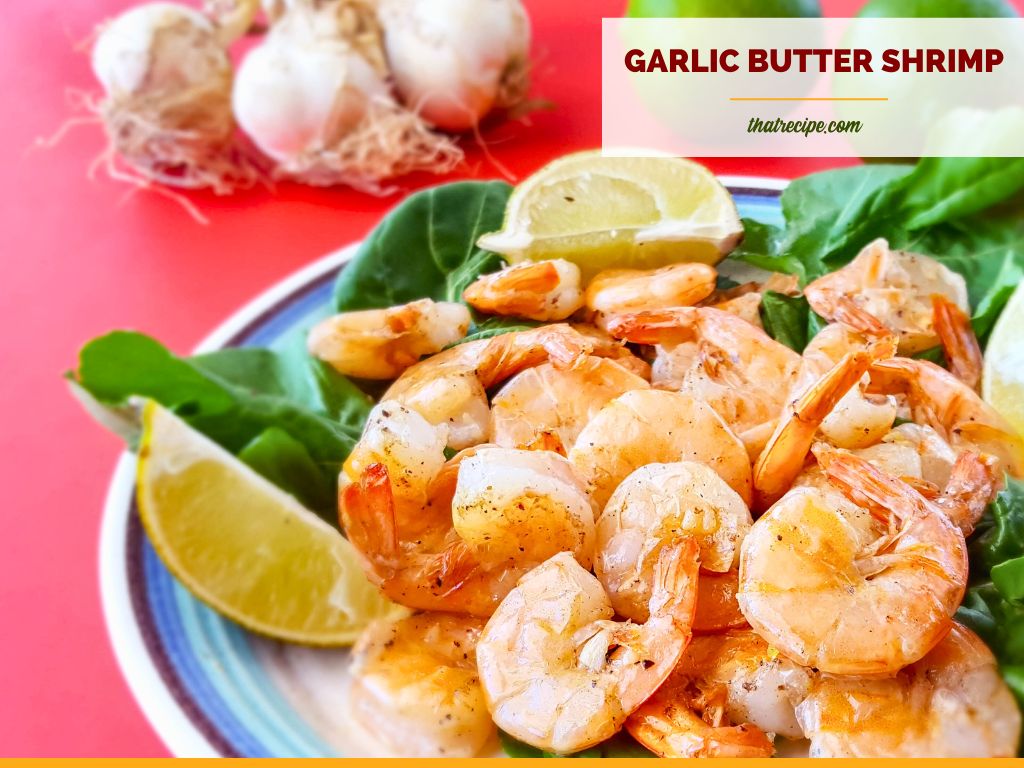 stir fried butter and garlic shrimp with limes and raw garlic in the background with text overlay "garlic butter shrimp"