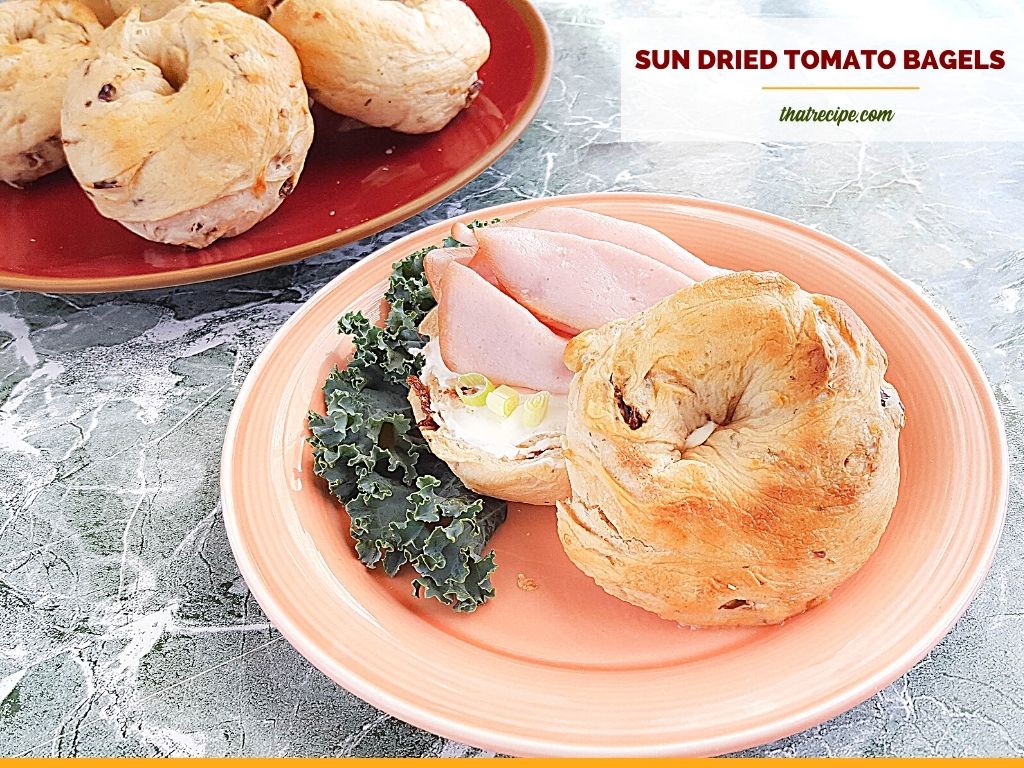 bagel sandwich on a plate with text overlay "sun dried tomato bagels"