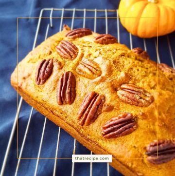 loaf of pumpkin spice bread on cooling rack with mini pumpkin